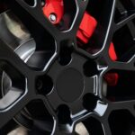 Rim de roues noires et étrier de frein rouge d'une voiture de sport.