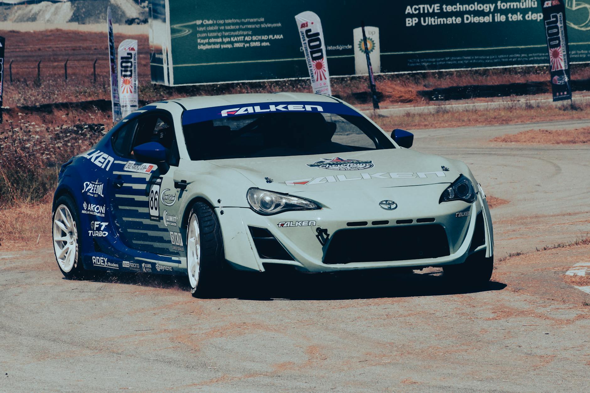 Voiture de course à grande vitesse prenant un virage serré lors d'une compétition sur piste de course en plein air.
