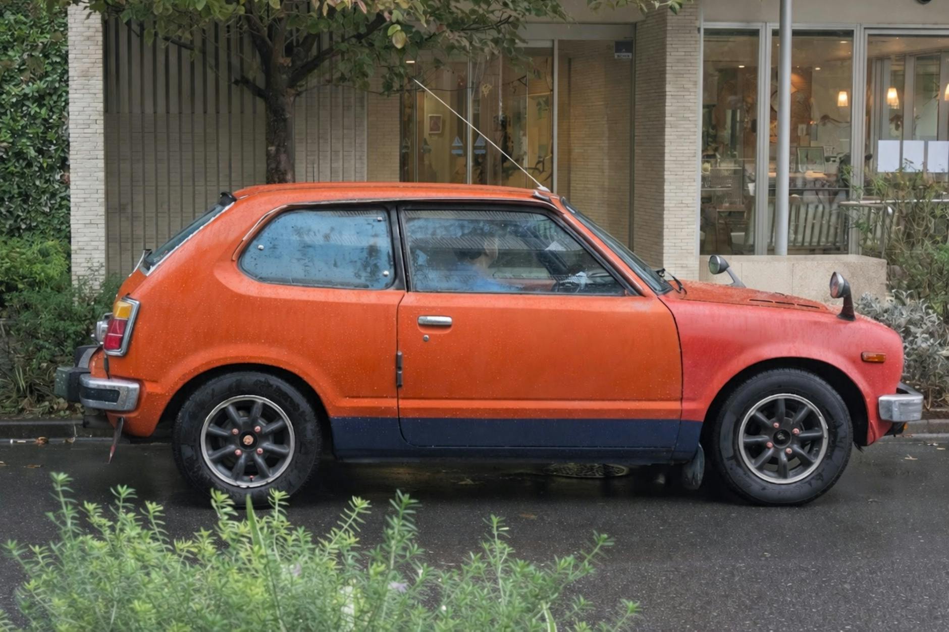 Voiture à hayon orange classique garée à l'extérieur dans une rue mouillée à Tokyo, au Japon.